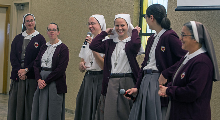 Sister Brooke Happ, of the Servants of the Pierced Hearts of Jesus and Mary, speaks into the microphone as Sister MacKenzie Gallagher displays her white veil, meaning that she is a novice in the community. Brown veils are for professed sisters and postulants wear ponytails, the sisters explained during the Focus 11 vocations rally that took place March 1 at St. Agatha Church, Miami.