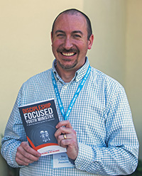 Eric Gallagher, one of several keynote speakers at the Archdiocese of Miami Youth Ministry Summit, holds a book he co-authored with Jim Beckman, "Discipleship Focused Youth Ministry."