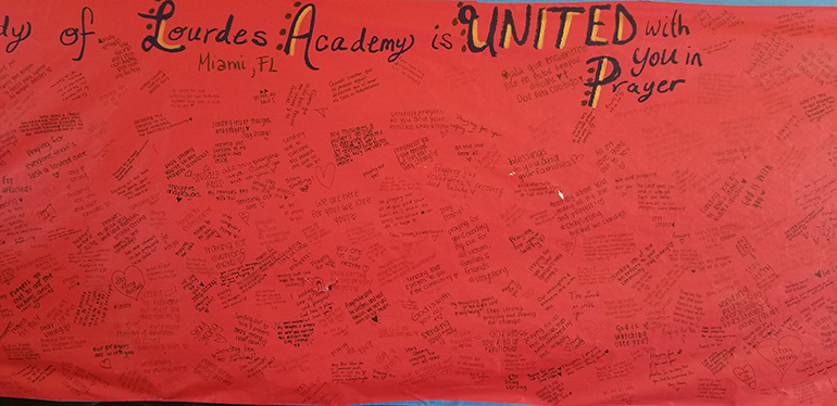 This huge banner signed by members of the student body, staff and faculty at Our Lady of Lourdes Academy in Miami was among the first to arrive at Mary Help of Christians Church after the Parkland shooting, which occurred just a mile down the road from the church and school.