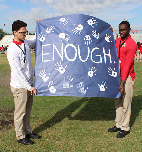 Seniors Orestes Gonzalez and Elvins Desarmes hold up a sign with 17 handprints in memory of the victims of the Marjory Stoneman Douglas High shootings during the walkout at Msgr. Pace High.
