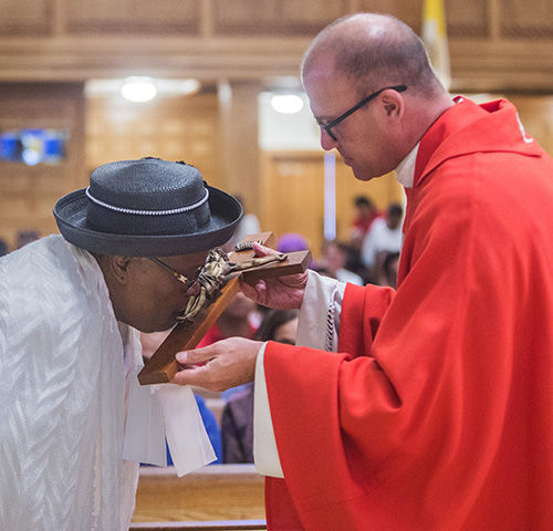 March 30, 2018
MARLENE QUARONI | FC
Father Christopher Marino, rector of St. Mary Cathedral, holds the cross as Marie Fleurimon kisses it.
Archbishop Thomas Wenski officiates at Good Friday service, the Liturgy of the Lord's Passion.