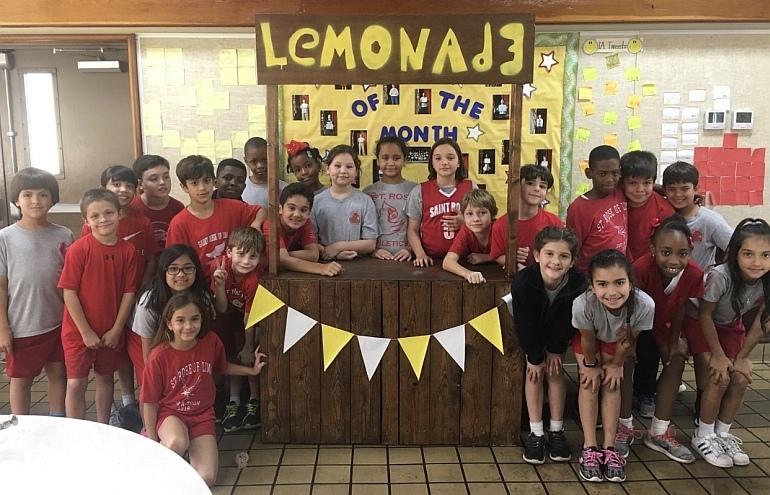 Third-graders at St. Rose of Lima School show the lemonade stand they operated for a charity. The students raised 0 over two days to provide clean water in Kenya.