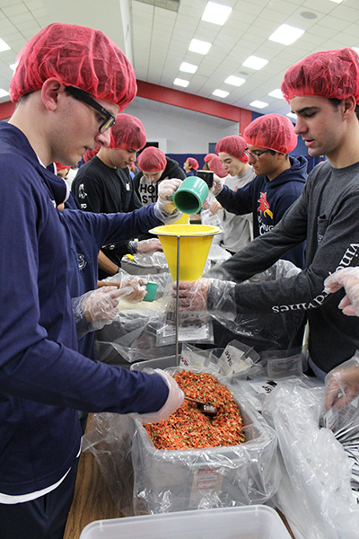 Students from Columbus High and Belen Jesuit Prep team up to pack meals.