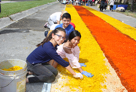 Los niños Marvea Chacon, Coni Sanchez y Edward, ayudan en la elaboración de la alfombra para la procesión de Viernes Santo en la parroquia Corpus Chisti, en Miami.