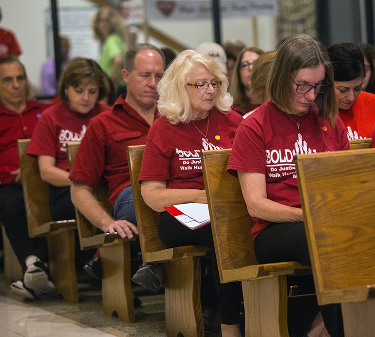 Members of St. Paul Lutheran Church, Weston, bow their heads as Archbishop Thomas Wenski leads the congregation in an opening prayer at BOLD Justice's 11th annual Nehemiah Action assembly, held April 23 at St. David Church in Davie.