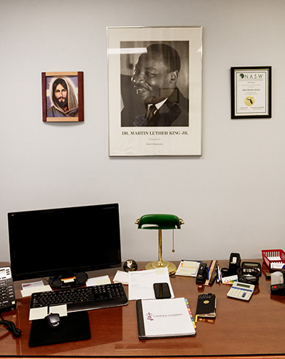 En su oficina en Wilton Manors, Peter Routsis-Arroyo, el nuevo director ejecutivo de Catholic Charities de la Arquidiócesis de Miami, muestra parte de su decoración personal, incluida una imagen tomada por Robert Sengstacke de Martin Luther King Jr.
