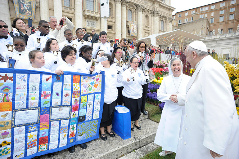 A very excited Sister Filomena Mastrangelo greets Pope Francis during the general audience at St. Peter's Square April 4 as members of the Marian Center hand bell choir ring their bells and hold the quilt they presented to the pope.