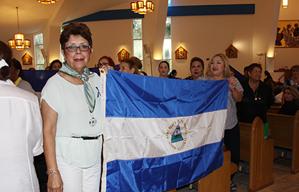 Nicaragua-born Elba Vanigas and Maria Eugenia Salmo hold up flags in support of the families of those who died, were injured or disappeared during the recent protests in their homeland. They were among those who took part in the Mass for Nicaragua at Our Lady of Divine Providence Church in Sweetwater.