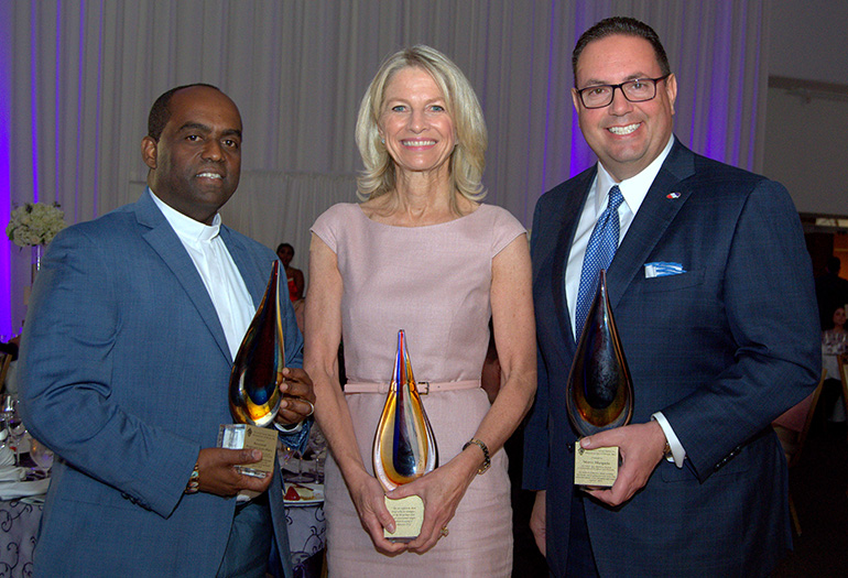 The three honorees show their New American Awards at the 20th anniversary gala for Catholic Legal Services in Miami on April 27. From left are Father Reginald Jean-Mary of Notre Dame d'Haiti Church; Julie Grimes, managing partner for a hotel chain; and Mario Murgado, CEO of a Miami-based auto dealership.