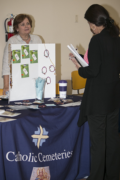 Estela Gomez, left, a senior family counselor at Catholic Cemeteries, answers questions from a Pastoral Center employee at the May 1 Health Fair.