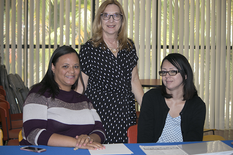 Health Plan staff wait to greet Pastoral Center employees coming to the Health Fair, from left, seated, Sugeily Trujillo and Brenda Hernandez; standing, Susan Waddell, director of the Health Plan.