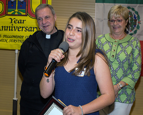 Daniela Hoyos, 13, thanks the Men's Club for her scholarship as Msgr. Pablo Navarro, St. John Neumann's pastor, and Maria Elena Villas, school principal, look on.