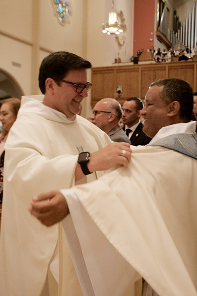 Father Jimmy Acevedo, left, helps vest his former parishioner at Mother of Our Redeemer, newly ordained Father Gustavo Barros.