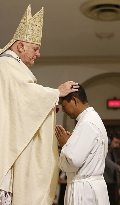 El Arzobispo Thomas Wenski impone las manos al diácono Juan Alberto Gómez, llamando al Espíritu Santo y ordenándolo como "sacerdote para siempre".