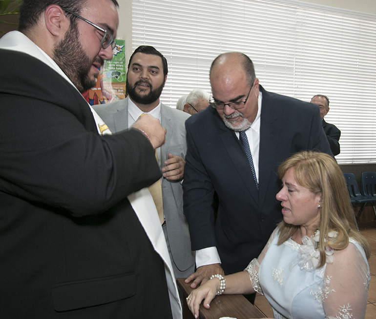 Después de la ceremonia de ordenación, en el salón parroquial de la Catedral St. Mary, el P. Matthew Gómez se limpia las lágrimas después de dar una de sus primeras bendiciones a sus padres, Fernando y Laura Gómez, mientras su hermano Mark observa.