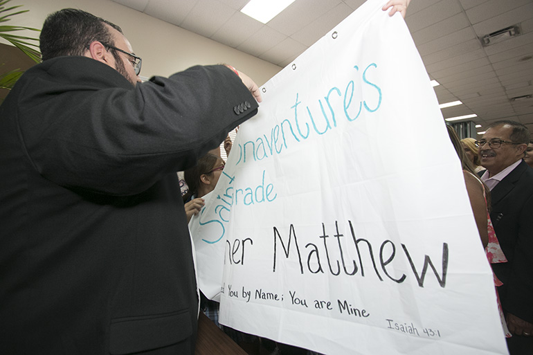 At the cathedral hall after the ceremony, Father Matthew Gomez exchanges "high-fives" with fifth-graders from St. Bonaventure School in Davie, who " adopted" him as a seminarian.