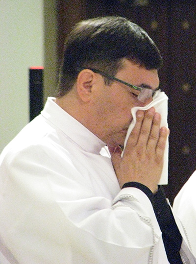 An emotional Father Omar Ayubi wipes away tears after Archbishop Thomas Wenski laid hands on him, ordaining him "a priest forever."