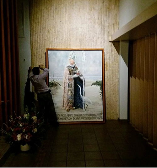 Jesus Mesa of Custom Quality Framing installs the paining "St. Augustine of Hippo," by Christopher Mangiaracina. Mesa donated his work building and installing the painting at St. Augustine Church and Student Center on Nov. 8, 2017.