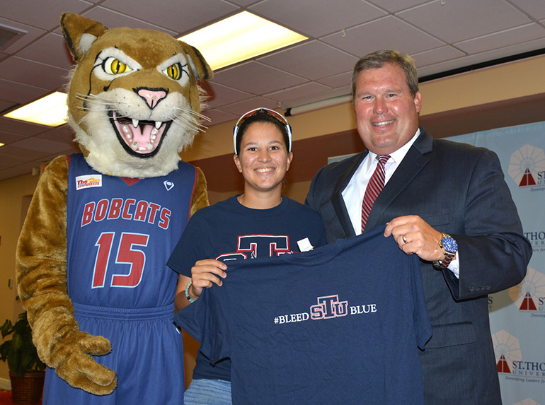 David A. Armstrong, presidente entrante de St. Thomas University, recibe una camiseta emblemática de manos de la estudiante Michelle Murch y de la mascota STU de la institución.
