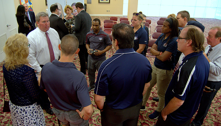 Sports program personnel flock around incoming St. Thomas University president David Armstrong, in white shirt and tie at left, after a Town Hall meeting June 4.