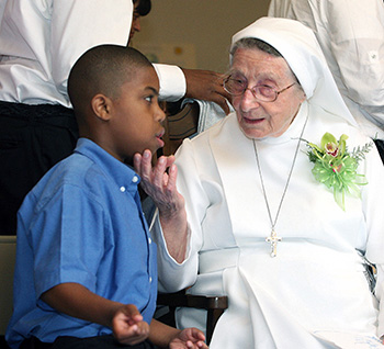 La Hna. Lucia Ceccotti conversa con el estudiante Ahmad Williams, de 9 años, en la celebración de su 90Âº cumpleaños.