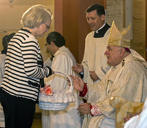 Martha Rodriguez de Perez, gives the basket with the names of loved ones who died recently to Archbishop Thomas Wenski.