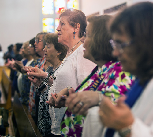 Members of the Miami Archdiocesan Council of Catholic Women recite the Lord's Prayer during the Mass at St. James Church where the MACCW presented layettes to seven Haitian mothers.