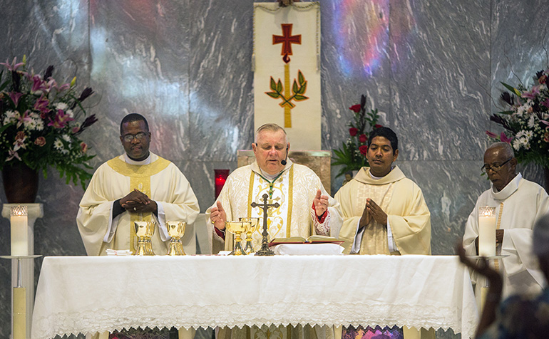 Archbishop Thomas Wenski celebrates Mass. At left is Msgr. Chanel Jeanty, St. James' pastor; at right is parochial vicar Father Juan Alberto Gomez.