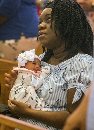 Cristina Cherizel holds her six-day old baby after the Mass at St. James Church where the MACCW presented layettes to eight Haitian mothers, including her.