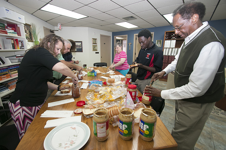 Busy assembling peanut butter sandwiches, from left: nt to back: Marcey Ayers, coordinator of special programs; Domenick Russo, coordinator of certification; Kim Pryzbylski, archdiocesan superintendent of schools; Hope Sadowski, administrative executive assistant; ADOM Virtual School student Samuel Ambroise; and Donald Edwards, associate superintendent of schools.