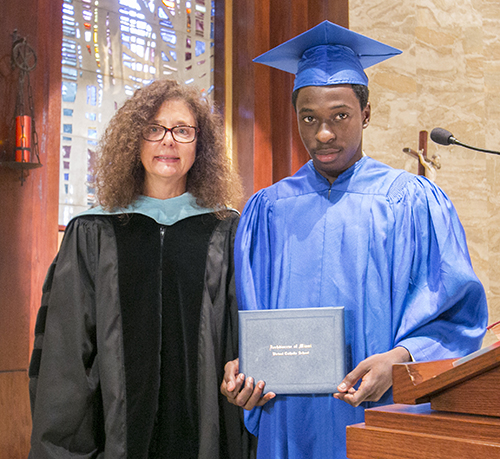 Samuel Ambroise, first local graduate of the Archdiocese of Miami Virtual Catholic School, receives his diploma from Superintendent Kim Pryzbylski.