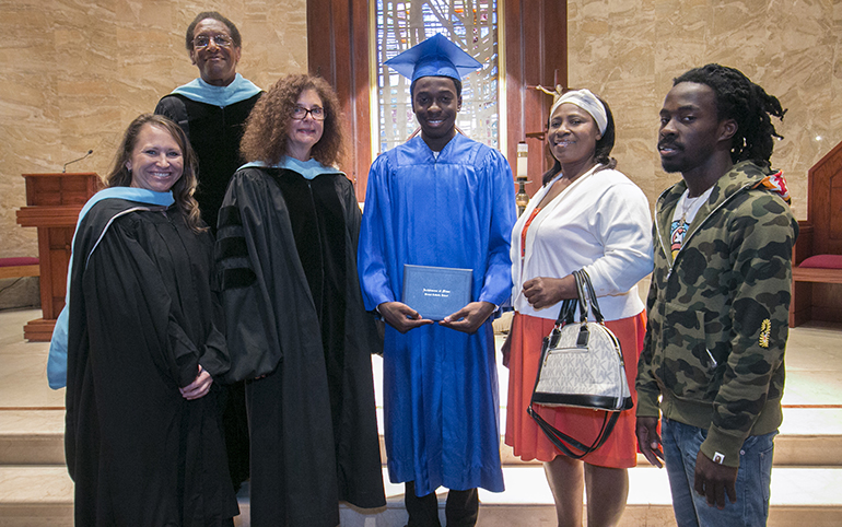 Samuel Ambroise, first local graduate of the Archdiocese of Miami Virtual Catholic School, poses with archdiocesan school officials and his family after his graduation Mass and ceremony; from left: Marcey Ayers, his virtual school teacher; Donald Edwards, associate superintendent; Kim Pryzbylski, superintendent; mother Ketty Ambroise and older brother Pekto.