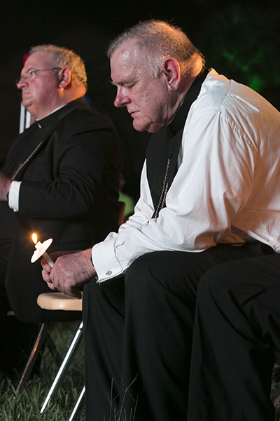 From left, Auxiliary Bishop Peter Baldacchino and Archbishop Thomas Wenski pray before the Blessed Sacrament at the Aug. 22 Wold Youth Day prayer vigil at St. John Vianney College Seminary.