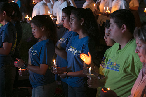 Participants pray by candlelight at the conclusion of adoration of the Blessed Sacrament, during the Aug. 22 World Youth Day prayer vigil at St. John Vianney College Seminary.