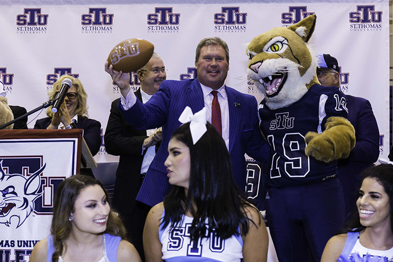 St. Thomas University President David Armstrong holds up a football as cheerleaders and the Bobcat mascot celebrate the announcement that the archdiocesan university will field a football team in 2019. The Bobcats will play in the Mid-South Conference of the National Association of Intercollegiate Athletics.