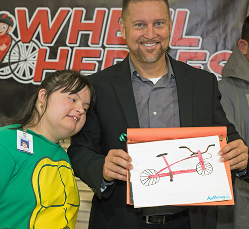 Marian Center student Valerie Virgil presents Anthony DiNito with a drawing of the cycle his non-profit donated to the school.