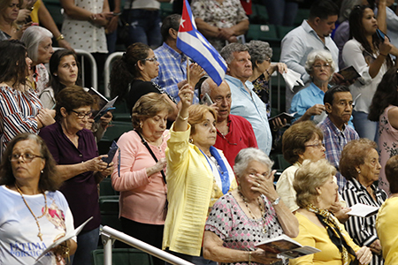 La gente agita banderas cubanas y pañuelos blancos mientras los miembros de Encuentros Juveniles llevan la imagen de Nuestra Señora de la Caridad alrededor del Watsco Center, antes de la Misa en su día de fiesta.