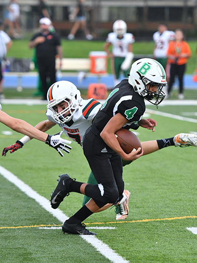 Sabres' sophomore receiver Jose Magarin (#4) escapes from Pinecrest defenders in St. Brendan High's first varsity football game in the school's  43-year history. St. Brendan won its opening game 28-0.