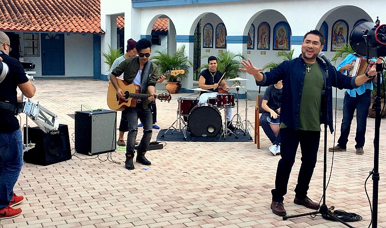 Iván Díaz canta mientras el grupo EPIC toca en el video de la canción "Nuestra Alegría", en el Instituto Pastoral para los Hispanos del Sureste, SEPI, en Miami como escenario. La canción fue la canción oficial de los jóvenes y jóvenes adultos de la reciente reunión del V Encuentro.