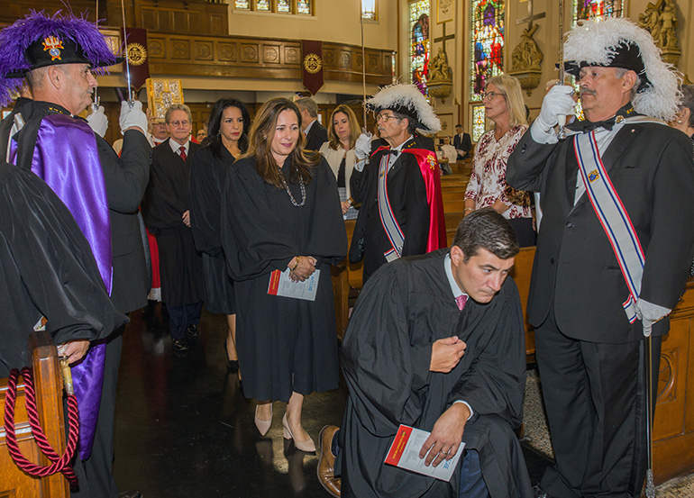 Circuit Court Judge Rodolfo Ruiz genuflects before the altar as Circuit Court Judges Monica Gordo, Beatrice Butchko and John Thornton walk behind him and Knights of Columbus Council 3201 honor guard line the aisle.