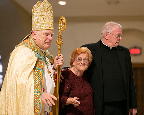 Father Randall Musselman, pastor of All Saints Parish in Sunrise, accompanies his parishioner, Antonia Ignaccolo, to receive her Jubilaeum Pin from Archbishop Thomas Wenski.