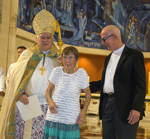 Archbishop Thomas Wenski gives Maryann Don of San Pablo Parish in Marathon the Jubilaeum pin her pastor, Father Luis Perez, stands beside her.