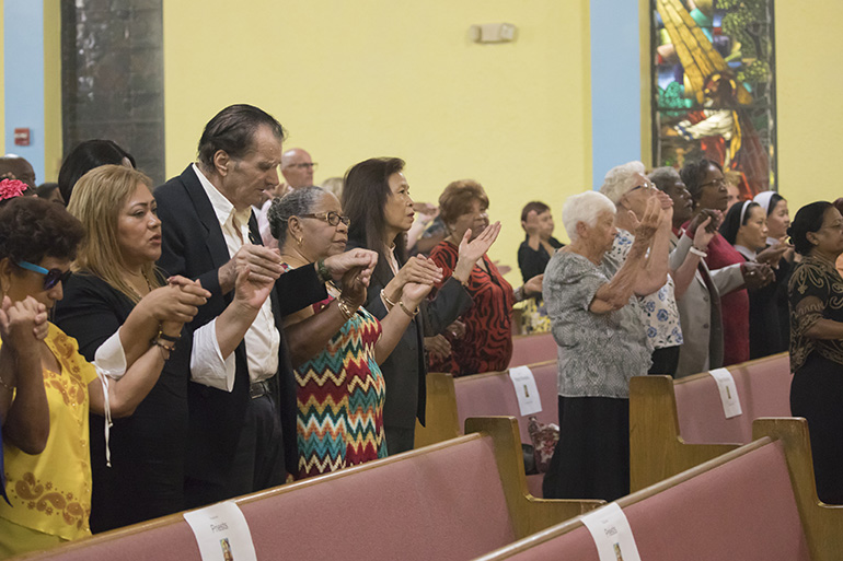 Parishioners hold hands during the "Our Father" prayer at the Mass celebrating St. Helen's 50th anniversary.