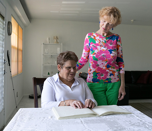 Coconut Creek resident Lygia Bohan, seated, who attends All Saints Parish in Sunrise, reads Catholic materials in braille, including the Sunday Mass readings which she reviews in advance of attending church. With her is Lighthouse Point resident and longtime disabilities advocate Dolores Hanley McDiarmid, who attends St. John the Baptist Church in Fort Lauderdale.