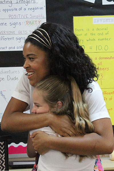 Amber Kemp-Gerstel, who admits she is a "hugger," receives a welcome hug from Brooke Beane, a young fan from Nativity School.