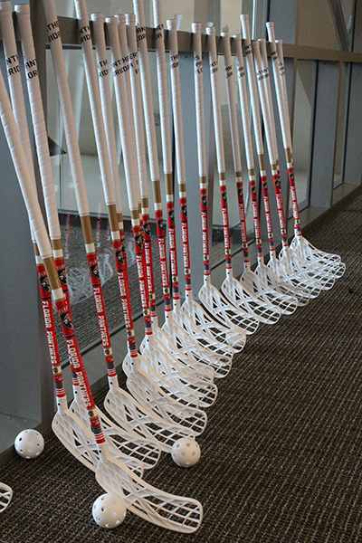 A view of the floorball sticks, which are smaller in height than hockey sticks, and more durable than the standard wooden sticks used in hockey. A ball similar to a wiffle ball is used, instead of a puck.
