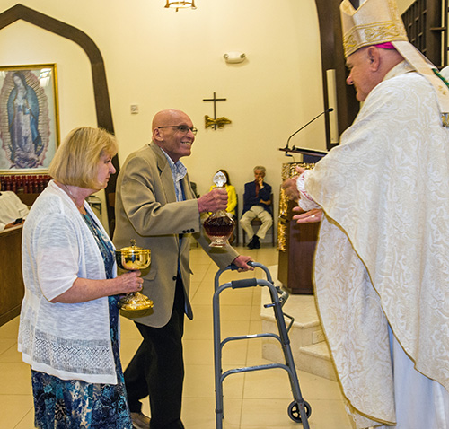 Founding parishioner Lou Huertas and Eileen Cahill, a parishioner since 1975, bring up the offertory to Archbishop Thomas Wenski.