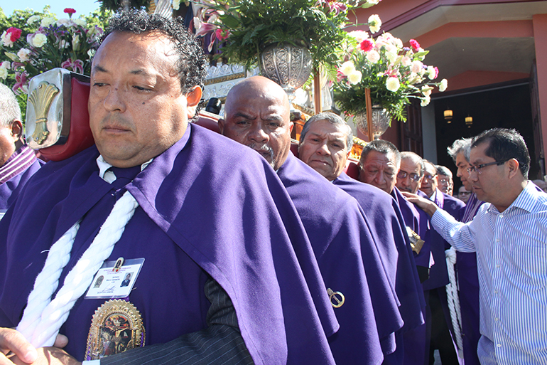 Marco Camacho (adelante), miembro de la Hermandad del Señor de los Milagros de la parroquia Good Shepherd, junto a otros miembros de diferentes Hermandades cargan en hombros la imagen del Cristo Morado que recorrerá el perímetro de la parroquia Corpus Christi en procesión.