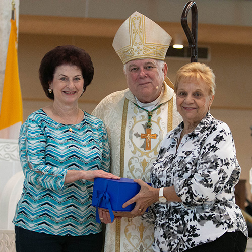 Camille Laurino, left, and Rosalie Constantino, pose with Archbishop Thomas Wenski after receiving this year's Esperanza Ginoris Award for excellence in a catechetical program. The annual Catechetical Day was held Nov. 3 at Archbishop McCarthy High School in Southwest Ranches.