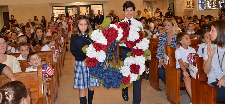 Fourth-grader Alessa Larosa and eighth grader David Rodriguez present a wreath during the Mass celebrated at St. Agnes Nov. 7 in remembrance of Veterans Day.